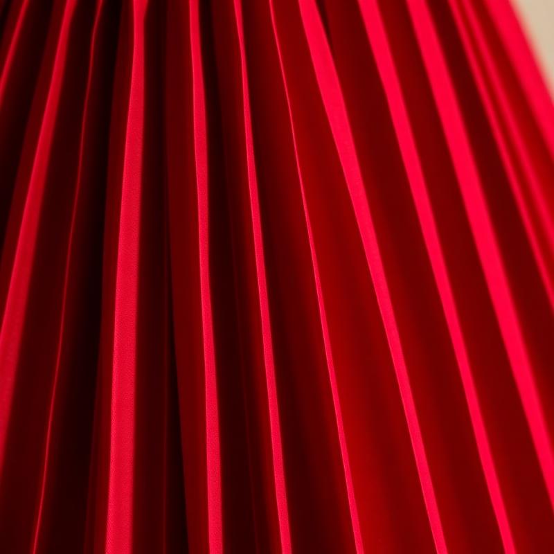 Close-up of knife-pleated skirt fabric in deep oxblood red.