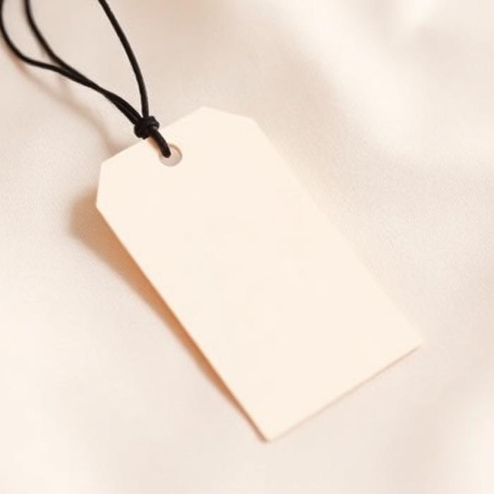 Cream card hang tag with black cord, resting on soft fabric.